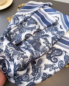 Detailed view of silk-like blue and white paisley scarf on a vintage gold tray