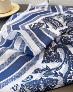 Detail of silk-like blue and white paisley scarf with elegant stripes and fine rolled edges