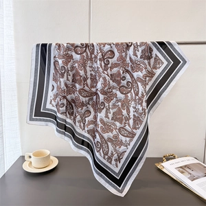 Elegant brown paisley silk-like scarf with striped border draped on a metal stand