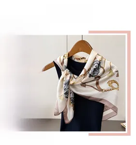 Detail of silk-like scarf featuring golden chain patterns and grey floral prints