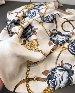 Detailed close-up of floral chain print silk scarf with clover pattern and gold accents