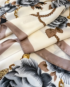 Close-up detail of luxury silk scarf with grey rose patterns and golden chain decor