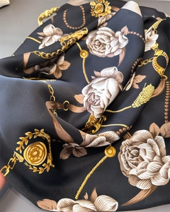 Detailed close-up of silk scarf showing golden chain and beige rose floral patterns