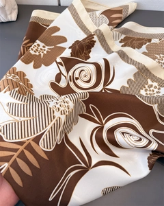 Detail of silk-like floral scarf with smooth texture and elegant brown print