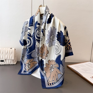 Elegant silk-like scarf with vintage floral prints and navy border hanging on a white hanger