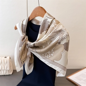Floral print faux silk square scarf in cream and brown styled on a blue sweater