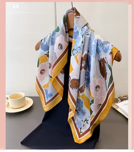 Floral silk-like scarf with yellow border and pink flowers draped on a wooden hook