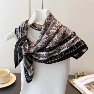 Detail of elegant paisley print silk scarf draped on a mannequin with French decor
