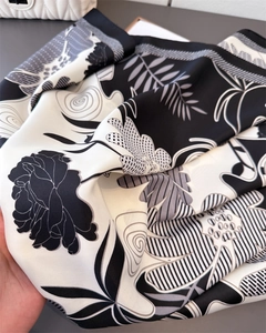 Detail of black and white floral satin scarf showing glossy texture and elegant pattern