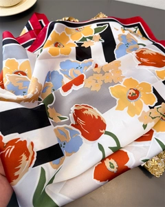 Detailed close-up of floral silk scarf fabric with vibrant colors and edge stitching