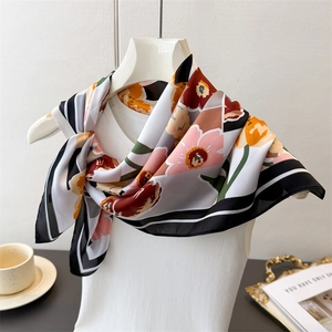 Detail of floral print silk scarf with striped edges displayed on a white hanger stand