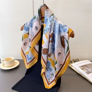 Detail of floral printed silk scarf with ginger and blue patterns on wood hanger