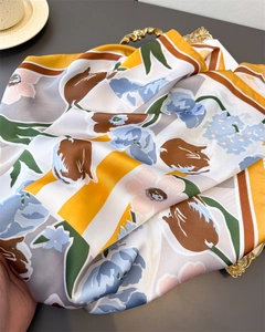 Detailed view of floral silk scarf with yellow edges on a vintage golden tray
