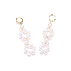 Detailed macro shot of baroque pearl earrings with gold-plated geometric drop pendants