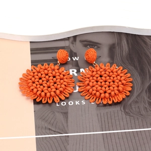 Detailed macro view of bohemian handmade bright orange sunflower beaded disk earrings