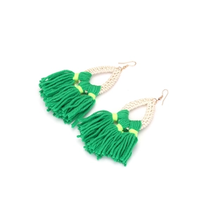 Detail of bohemian rattan woven earrings with vibrant green fringe and gold fishhooks