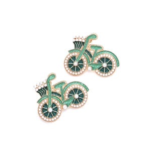 Détail de boucles d'oreilles vélo en émail vert avec perles blanches et doré