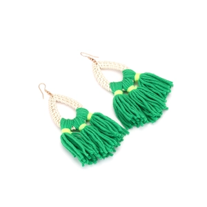 Detail of bohemian rattan drop earrings with vibrant green fringe tassels and gold hooks