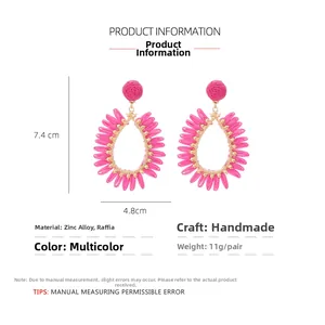Détail de boucles d'oreilles gouttes en raphia fuchsia faites main avec dimensions 7,4x4,8cm