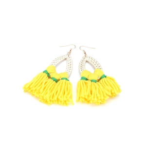 Detail of bohemian drop earrings with white rattan weave and vibrant yellow yarn tassels