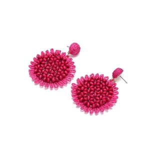 Detail of handmade fuchsia raffia sunflower earrings with central beaded cluster