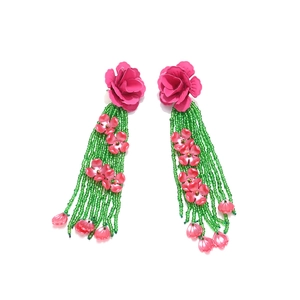 Détail de boucles d'oreilles florales en perles avec roses roses et pompons verts