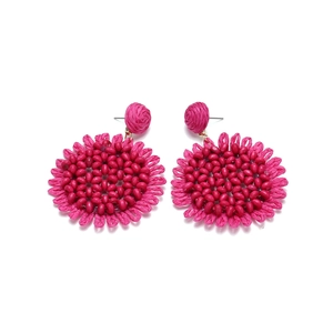 Detail of rose red woven raffia sunflower earrings with beaded accents on white background