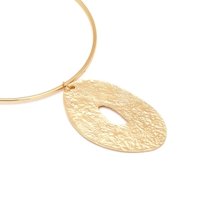 Macro detail of gold-tone collar necklace with hammered texture hollow oval pendant