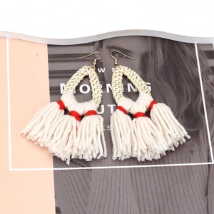 Detailed shot of bohemian straw woven earrings with thick white fringe and red accents