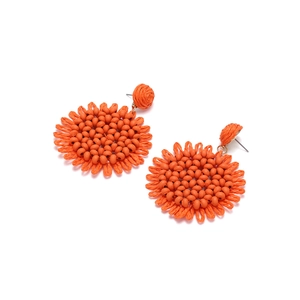 Detailed view of handmade woven sunflower earrings with orange seed beads and raffia texture