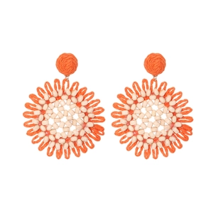 Close-up of handmade Bohemian raffia flower earrings with orange weave and wood beads