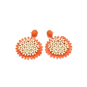Close-up of handmade woven raffia sunflower earrings with bright orange petals and beads