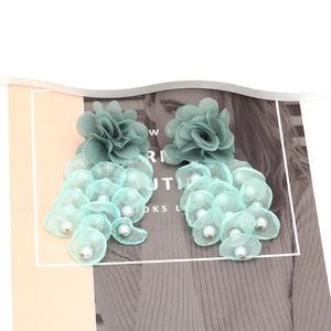 Detail of mint green mesh petal earrings with white pearls on a fashion magazine background