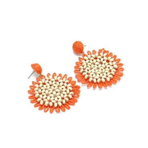 Detail showing orange woven raffia sunflower earrings with small white beads center