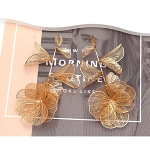 Elegant gold hollow flower drop earrings with mesh petals on fashion magazine backdrop