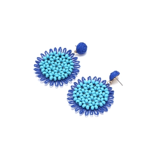 Detail of bohemian raffia woven sunflower earrings with blue bead center and petals