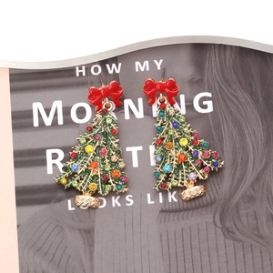 Boucles d'oreilles sapin de Noël avec cristaux colorés et nœud rouge sur magazine