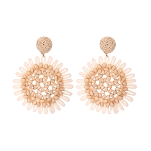Close-up of bohemian raffia sunflower earrings with woven texture and central bead detail