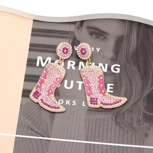 Boucles d'oreilles bottes de cowboy roses avec strass brillants et perles sur magazine