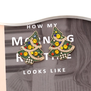 Detail of Christmas tree earrings with colorful rhinestones and green enamel accents