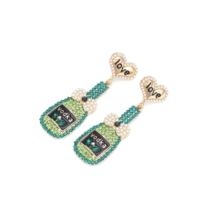 Détail de boucles d'oreilles cœur love avec pendentif bouteille vodka et strass verts