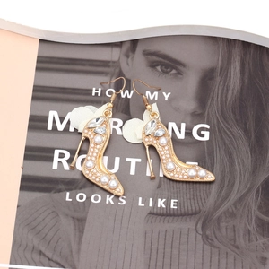 Détail de boucles d'oreilles talons hauts avec perles, cristaux et nœud blanc sur magazine