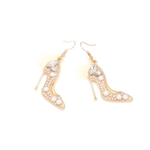 Détail de boucles d'oreilles talons hauts avec perles blanches, strass et nœuds en tulle