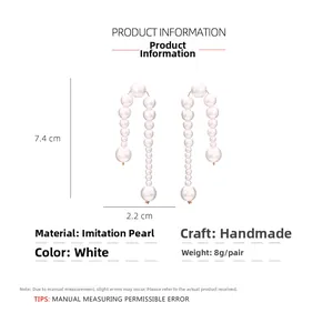 Detail showing U-shaped earrings with handmade white imitation pearls and metal frame