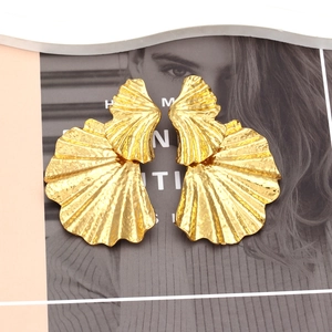 Boucles d'oreilles feuille de ginkgo dorées texturées sur fond de magazine de mode