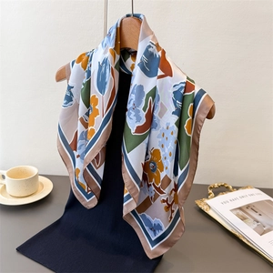 Close-up of elegant floral silk scarf with vibrant prints displayed on a wooden hanger