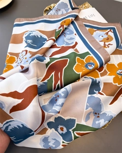 Close-up of silk scarf with floral and geometric patterns in navy, mustard, and green