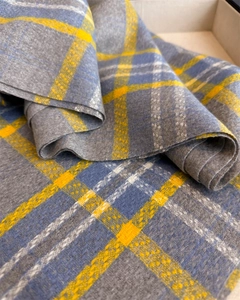 Detalle de la textura de la bufanda a cuadros gris y amarillo con flecos suaves