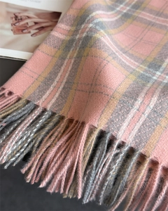 Detalle en primer plano de bufanda de cuadros rosa y gris con textura suave y flecos largos