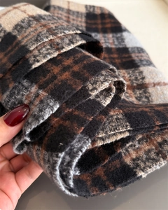 Gros plan sur la texture d'une écharpe à carreaux épaisse avec détails de franges doux